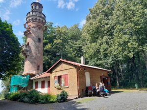 7 Celkový pohled na rozhlednu z červených cihel ( vlevo), přístavek s bufetem (uprostřed) a skupinka členů SONS na lavičkách (vpravo)