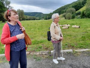 Dvě členky SONS pózují u louky s odpočívajícími ovcemi