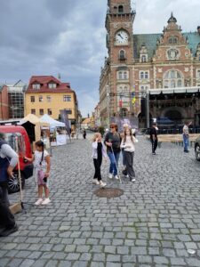 Členka SONS se svými vnučkami kráčí po náměstí ve Frýdlantě - v pozadí frýdlantská radnice